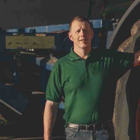 Image of a man standing next to a tractor wheel