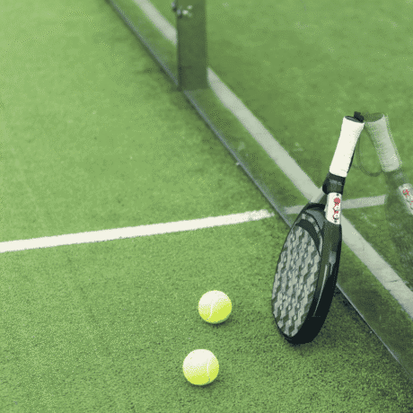 Image of a padel court with a racket and two balls